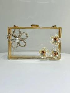 Close-up of transparent acrylic evening bag with gold metal frame and floral rhinestone