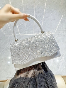 Detailed view of silver sparkly evening bag with sequins and metallic top handle
