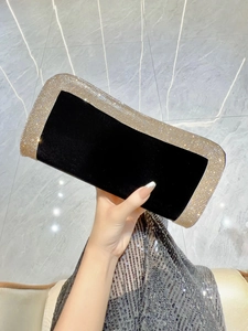 Dettaglio della pochette in velluto nero con strass dorati su abito di paillettes argento
