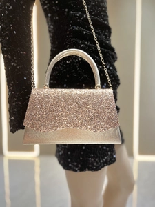 Detail of champagne gold evening clutch with glitter texture and elegant metal handle