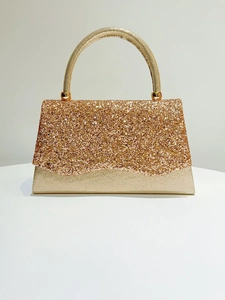 Close-up of golden sequined evening bag with metallic handle and shimmering texture