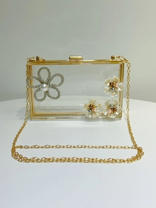 Detailed view of acrylic evening clutch with rhinestone flowers and gold chain strap