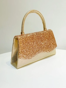 Detailed side view of golden glitter evening clutch bag with metallic handle