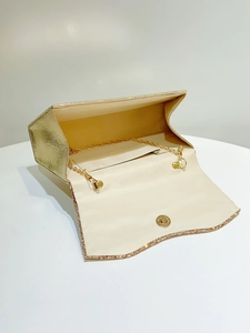 Detailed interior of a gold evening clutch showing magnetic clasp and gold chain strap