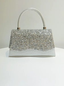 Detail of silver sparkling sequins on a trapezoid evening clutch bag with round metal handle