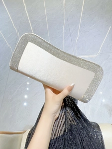Dettaglio dell'elegante pochette in raso avorio con bordi in strass luccicanti
