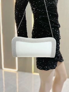 Dettaglio della pochette da sera in raso bianco con strass luccicanti e catena argento