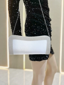 Dettaglio di una pochette da sera bianca con bordi di strass argento e catenina sottile