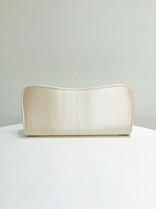 Dettaglio dell'elegante pochette da sera in raso oro champagne su tavolo bianco