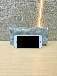 Elegant silver rhinestone evening clutch with crystal tassels shown beside a smartphone