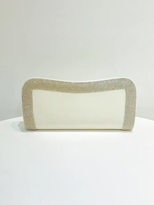 Dettaglio di una pochette da sera in raso bianco con eleganti bordi decorati con strass
