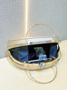 Detail of champagne evening clutch bag with crystal flower clasp and gold ring handle