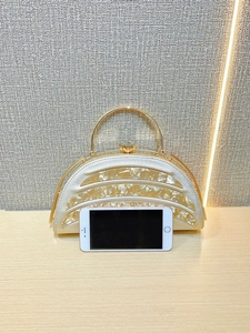 Detail of golden semi-circle evening clutch bag with metal handle and gemstone lock