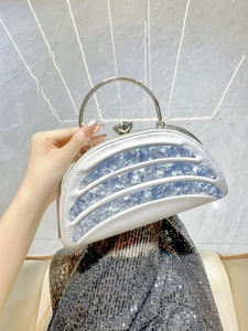 Detailed macro view of silver evening bag featuring crystal knob lock and blue stone panels