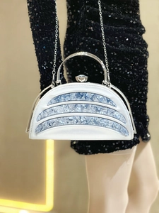 Detail of silver evening bag with blue stone inlay and crystal clasp on black sequin dress