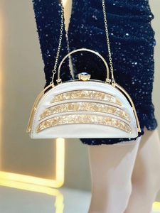 Detail of silver evening clutch with amber curved stripes and blue crystal clasp accent