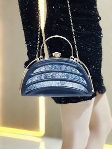 Detail of luxury black evening clutch with blue marble accents and gold handle on gown