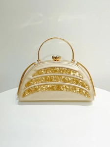 Macro view of gold evening clutch featuring amber wave texture and rhinestone clasp