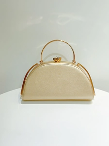 Detail of champagne gold evening clutch featuring a semi-circular shape and glitter texture