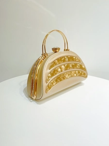 Detail of champagne gold evening bag with shell textured panels and crystal ring handle