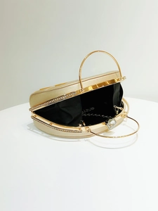Detailed side view of golden semi-circle evening bag with rhinestone trim and floral crystal clasp
