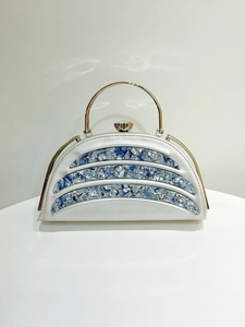 Detailed front view of silver evening bag with marble stripes and gold round handle