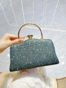Close-up of emerald green sequin evening bag with gold metal handle and jewel clasp