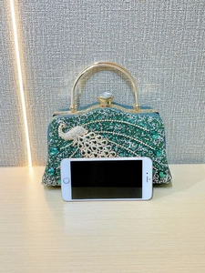 Detailed macro view of peacock-shaped evening clutch with green rhinestones and gold handle