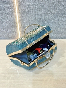 Macro detail of luxury green rhinestone evening bag interior with gold metal handle
