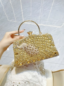 Detailed close-up of a golden peacock evening clutch with sparkling rhinestones decoration