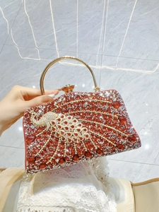 Macro shot of red rhinestone evening clutch bag with ornate gold peacock decoration