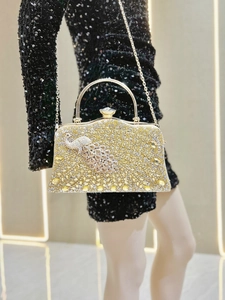 Macro detail of gold evening bag with peacock jewel ornament and full rhinestone finish