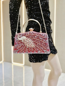 Close-up of red rhinestone evening bag featuring a crystal peacock design and gold handle