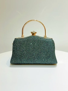 Detail of dark green sequin clutch with golden handle and large gemstone clasp