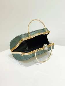 Detail of emerald green sequin evening clutch with gold handle and crystal clasp