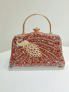 Detail of red rhinestone evening bag featuring a golden peacock pattern and gem clasp