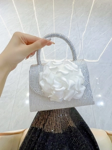 Close-up of sparkling silver rhinestones and a large white satin flower on the handbag