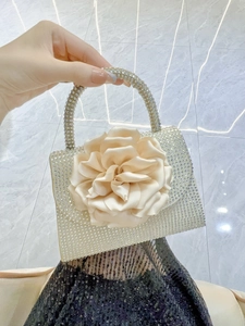 Close-up of a satin rose and sparkling rhinestones on the champagne evening handbag