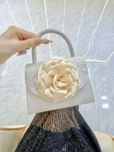 Detail of a silver rhinestone evening bag featuring a large beige satin 3D rose flower