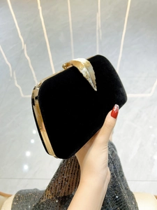 Elegant black velvet evening clutch with gold leaf clasp held against a sequin dress
