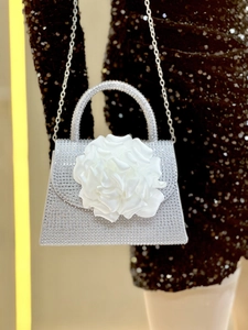 Macro shot of a silver rhinestone evening bag featuring a white satin 3D rose detail