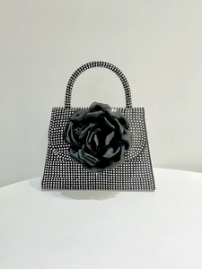 Detail of black evening bag featuring a large 3D fabric rose and sparkling silver rhinestones