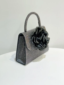 Detailed view of luxury evening bag with full sparkling rhinestones and black satin rose