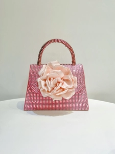 Close-up of pink luxury evening bag with shimmering crystals and large fabric rose