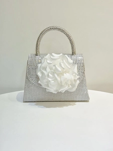 Detail of silver rhinestone evening bag featuring a 3D white fabric flower embellishment