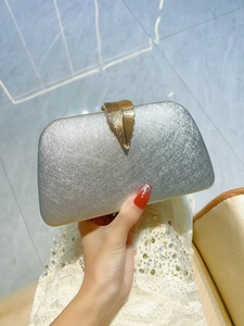 Detail of silver brushed evening clutch with elegant gold leaf buckle for weddings