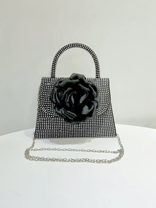 Detail of black fabric rose flower and sparkling rhinestones on an evening handbag