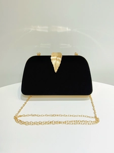 Detail of black velvet evening clutch featuring a delicate gold leaf clasp and chain