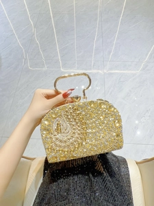 Detalle de elegante bolso de noche de cristal dorado con asa de metal y logotipo