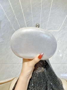 Close-up of silver glitter evening clutch bag with a rhinestone ball clasp and metal fabric